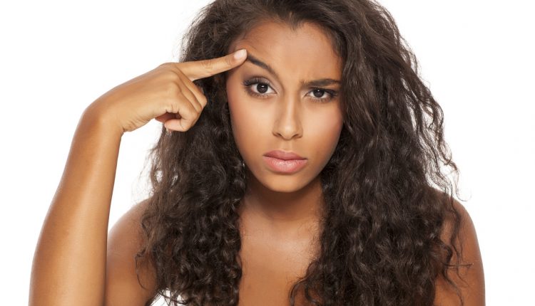 portrait of a beautiful young dark-skinned woman, lift her eyebrow with her finger on a white background